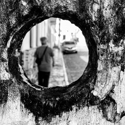 Man walking, framed by a circular hole in the foreground.